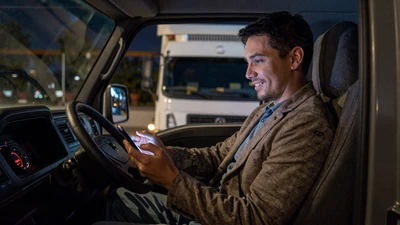 Truck driver using a smartphone in a cab at night - best dating apps for CDL drivers