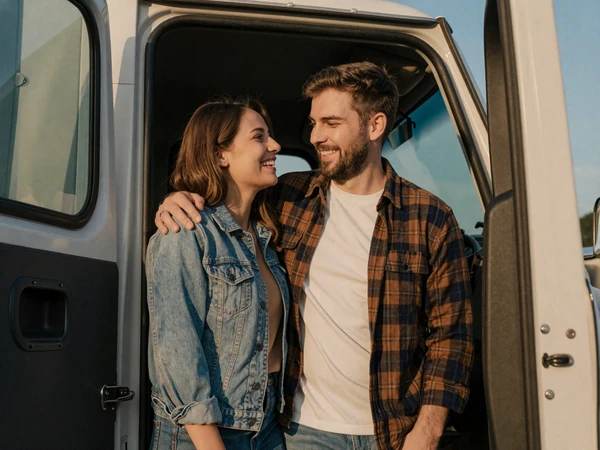 Happy couple by a semi-truck cab at golden hour - trucker wife life on DriveMatch